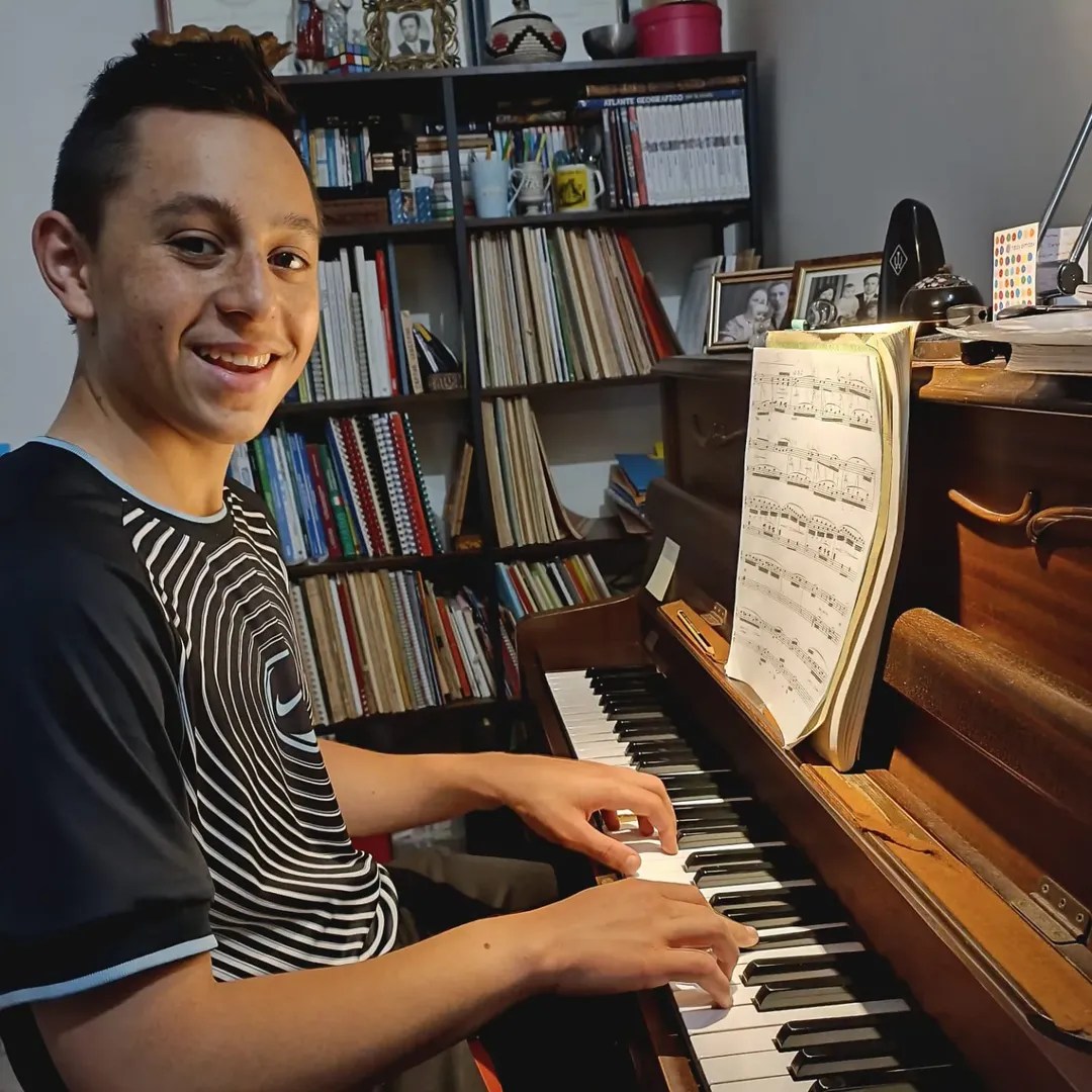 Ragazzo di 16 anni al pianoforte sorride guardando l’obiettivo durante una lezione a Roma